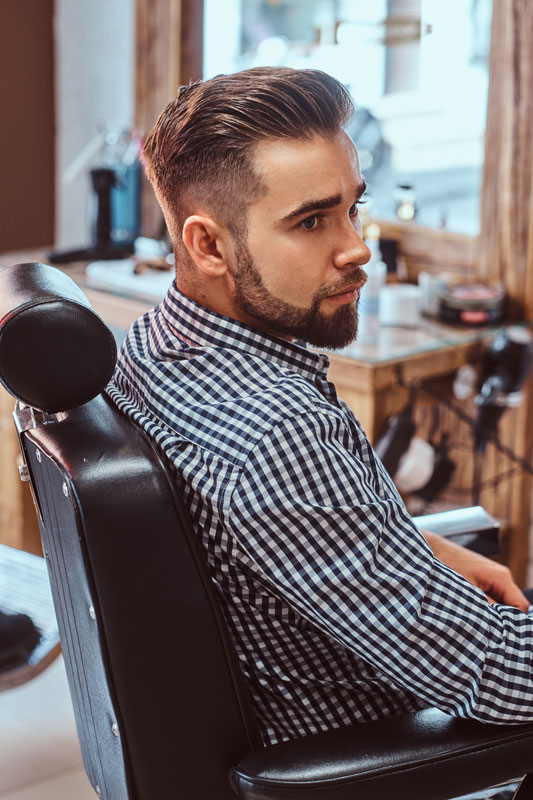 attractive-pensive-man-is-waiting-his-turn-get-haircut-busy-barbershop